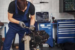 professioneel klusjesman in garage werken met gebroken auto- motor foto