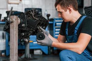 professioneel klusjesman in garage werken met gebroken auto- motor foto