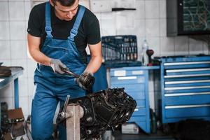 professioneel klusjesman in garage werken met gebroken auto- motor foto