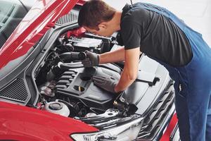 top visie van mannetje arbeider in uniform dat reparaties rood auto- foto