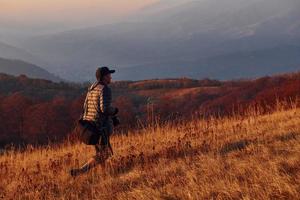 mannetje fotograaf staand en werken Bij majestueus landschap van herfst bomen en bergen door de horizon foto