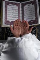 kind hand- bidden met verheven handen tegen de koran achtergrond. Islamitisch concept foto