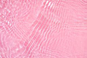 onscherp wazig transparant roze gekleurde Doorzichtig kalmte water oppervlakte structuur met spatten en bubbels. modieus abstract natuur achtergrond. water golven in zonlicht met kopiëren ruimte. roze waterverf schijnend foto