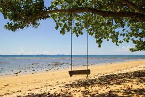 reizen naar eiland koh lanta, Thailand. de schommel onder de boom Aan de zand strand in de buurt naar de zee. foto