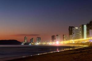 mazatlan sinaloa strand Bij nacht met lichtgevend stad in de achtergrond foto