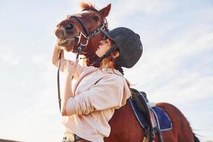 mooi zonneschijn. jong vrouw staand met haar paard in landbouw veld- Bij dag foto