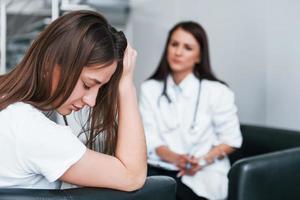 meisje hebben mentaal afbreken en huilen. jong vrouw hebben een bezoek met vrouw dokter in modern kliniek foto