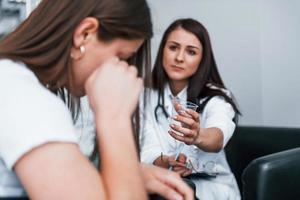 meisje hebben mentaal afbreken en huilen. jong vrouw hebben een bezoek met vrouw dokter in modern kliniek foto