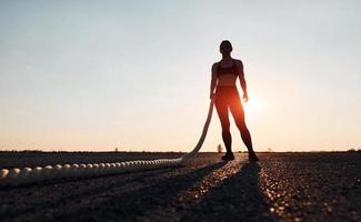 vrouw in sportkleding opleiding met knopen Aan de weg Bij avond tijd foto