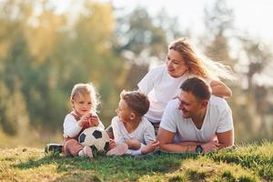 met voetbal bal. gelukkig familie aan het liegen naar beneden buitenshuis in de buurt de Woud. met dochter en zoon foto