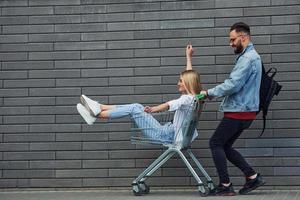 hebben pret en rijden boodschappen doen kar. jong elegant Mens met vrouw in gewoontjes kleren buitenshuis samen. opvatting van vriendschap of relaties foto