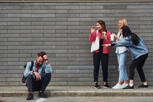 drie Dames staand en lachend Bij vent dat zittend buitenshuis in de buurt gebouw Bij dag foto