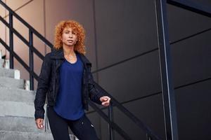 jong Europese roodharige vrouw hebben wandelen Aan de trap buitenshuis foto