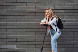 mooi blond in gewoontjes kleren rijden elektrisch schieter buitenshuis Bij zonnig dag foto