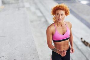 jong Europese roodharige vrouw in sportief kleren rennen buitenshuis foto