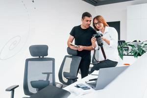 Mens in zwart kleren aan het kijken foto's Aan de vrouwelijk fotograaf camera foto