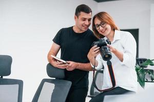 Mens in zwart kleren aan het kijken foto's Aan de vrouwelijk fotograaf camera foto