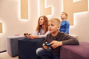 vrolijk kinderen zittend binnenshuis en spelen video spellen samen foto