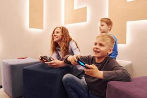 vrolijk kinderen zittend binnenshuis en spelen video spellen samen foto