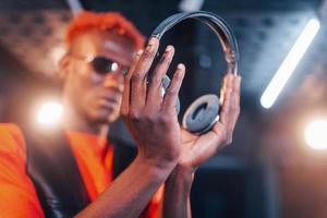 jong Afrikaanse Amerikaans performer staand in een opname studio en Holding hoofdtelefoons foto