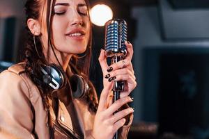 jong mooi vrouw zanger repeteren in een opname studio foto