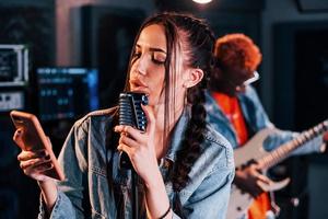 vent Toneelstukken gitaar, meisje zingt. Afrikaanse Amerikaans Mens met wit meisje repeteren in de studio samen foto