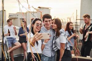 nemen selfie. groep van jong mensen in gewoontjes kleren hebben een partij Bij op het dak samen Bij dag foto