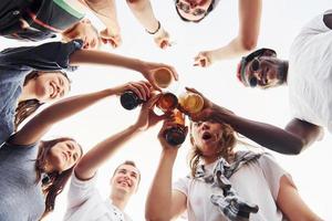 visie van onderstaand. aan het doen proost. groep van jong mensen in gewoontjes kleren hebben een partij Bij op het dak samen Bij dag foto