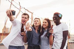 staand samen en nemen selfie. groep van jong mensen in gewoontjes kleren hebben een partij Bij op het dak samen Bij dag foto