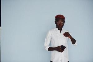 jong Afrikaanse Amerikaans Mens in wit formeel kleren staand tegen muur binnenshuis foto