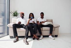 groep van Afrikaanse Amerikaans mensen in formeel kleren zittend Aan sofa binnenshuis in kantoor samen foto