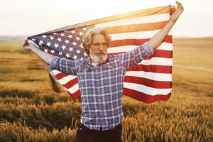 patriottisch senior Mens staand Aan de veld- met Verenigde Staten van Amerika vlag. opvatting van vrijheid foto