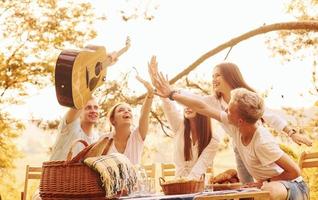 geven hoog vijf naar elk ander. groep van jong mensen hebben vakantie buitenshuis in de Woud. opvatting van weekend en vriendschap foto