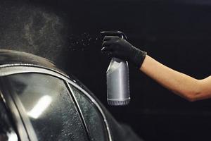 sproeien de voertuig. modern zwart auto- krijgen schoongemaakt door vrouw binnen van auto wassen station foto