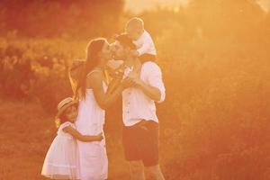 verlichte bu zonlicht. familie van vier mensen uitgeven vrij tijd Aan de veld- Bij dag tijd van zomer foto