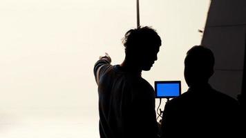 film regisseur en fotograaf zijn pratend of overleg plegen naar maken studio reeks voordat het schieten video en silhouet achtergrond verlichting. foto