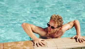 Mens in zwart zonnebril is in zwemmen zwembad Bij zijn vakanties foto