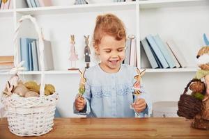 schattig weinig meisje spelen met speelgoed wanneer vieren Pasen vakantie binnenshuis foto