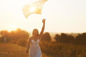 vrolijk vrouw hebben pret met vlieger buitenshuis Aan de veld- Bij zomertijd en glimlacht foto