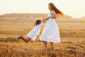 positief weinig meisje met haar moeder hebben weekend buitenshuis Aan de zomer veld- samen foto