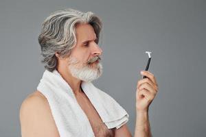 opvatting van scheren. elegant modern senior Mens met grijs haar- en baard is binnenshuis foto