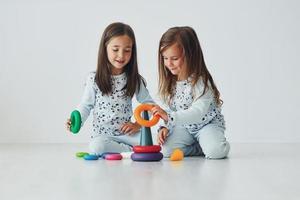 spelen met speelgoed. twee schattig weinig meisjes binnenshuis Bij huis samen. kinderen hebben pret foto