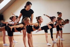 trainer is helpen. groep van vrouw kinderen beoefenen atletisch opdrachten samen binnenshuis foto