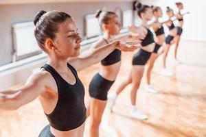 staand in de rij. groep van vrouw kinderen beoefenen atletisch opdrachten samen binnenshuis foto