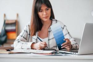 aan het doen papierwerk. jong vrouw freelance arbeider is binnenshuis in huis Bij dag foto