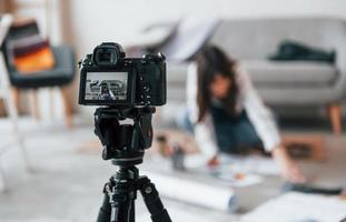 camera is Aan de vloer. jong vrouw freelance arbeider is binnenshuis in huis Bij dag foto