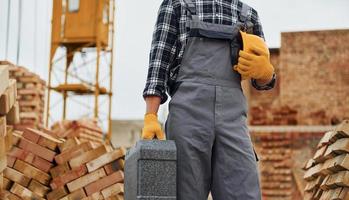 moeilijk hoed en geval in handen. bouw arbeider in uniform en veiligheid uitrusting hebben baan Aan gebouw foto