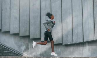 opvatting van sport. jong Afrikaanse Amerikaans vrouw in sportief kleren hebben training buitenshuis Bij dag foto