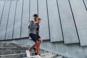 in de buurt groot muur. Europese Mens en Afrikaanse Amerikaans vrouw in sportief kleren hebben training samen foto