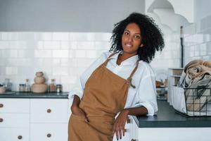 Aan de keuken. jong Afrikaanse Amerikaans vrouw met gekruld haar- binnenshuis Bij huis foto